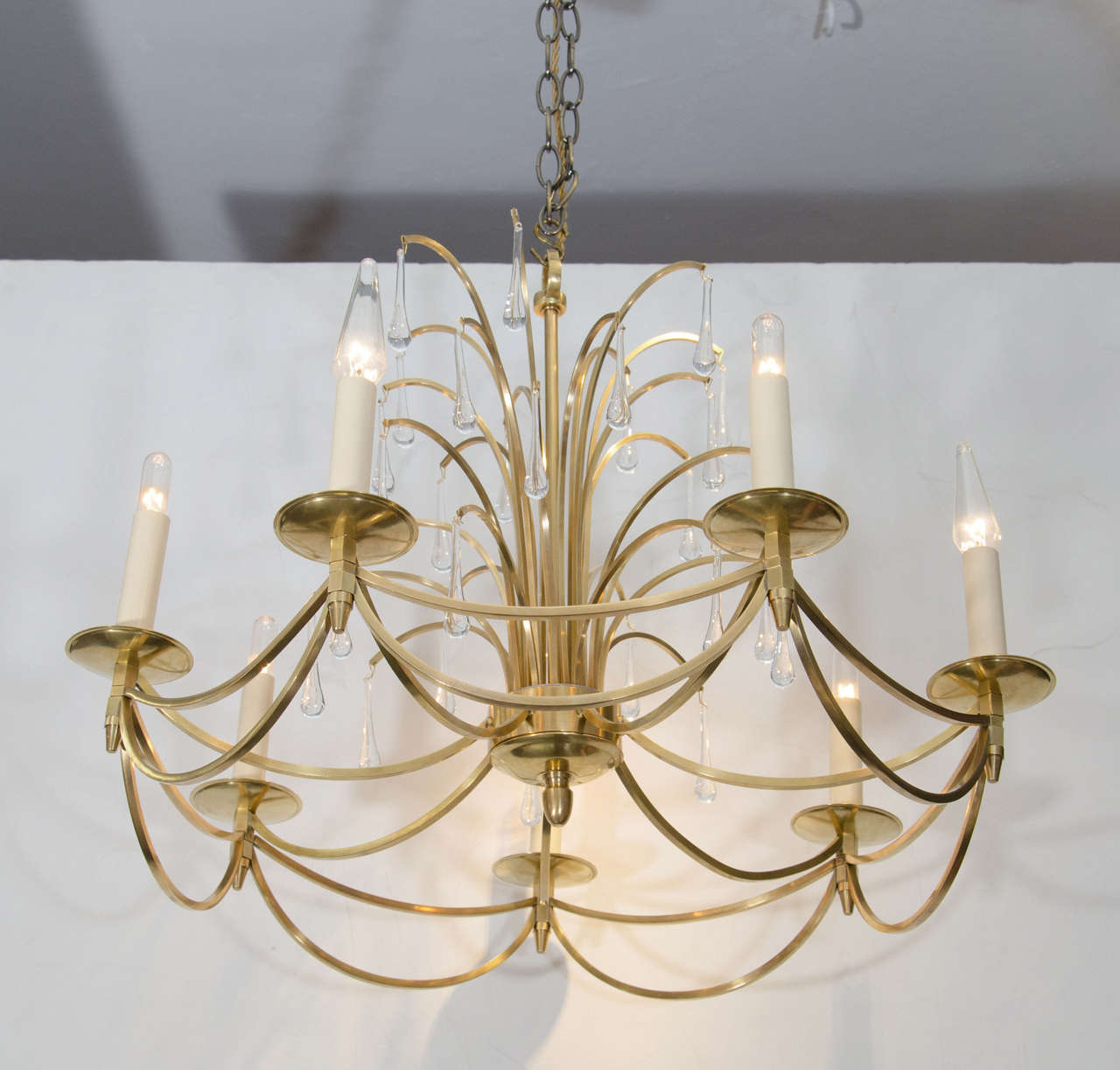A vintage, circa 1960s Swedish waterfall style chandelier, made of polished brass with hanging teardrop formed crystals. Each has seven candelabra style sockets, for candelabra sized bulbs. Good vintage condition with age appropriate wear.