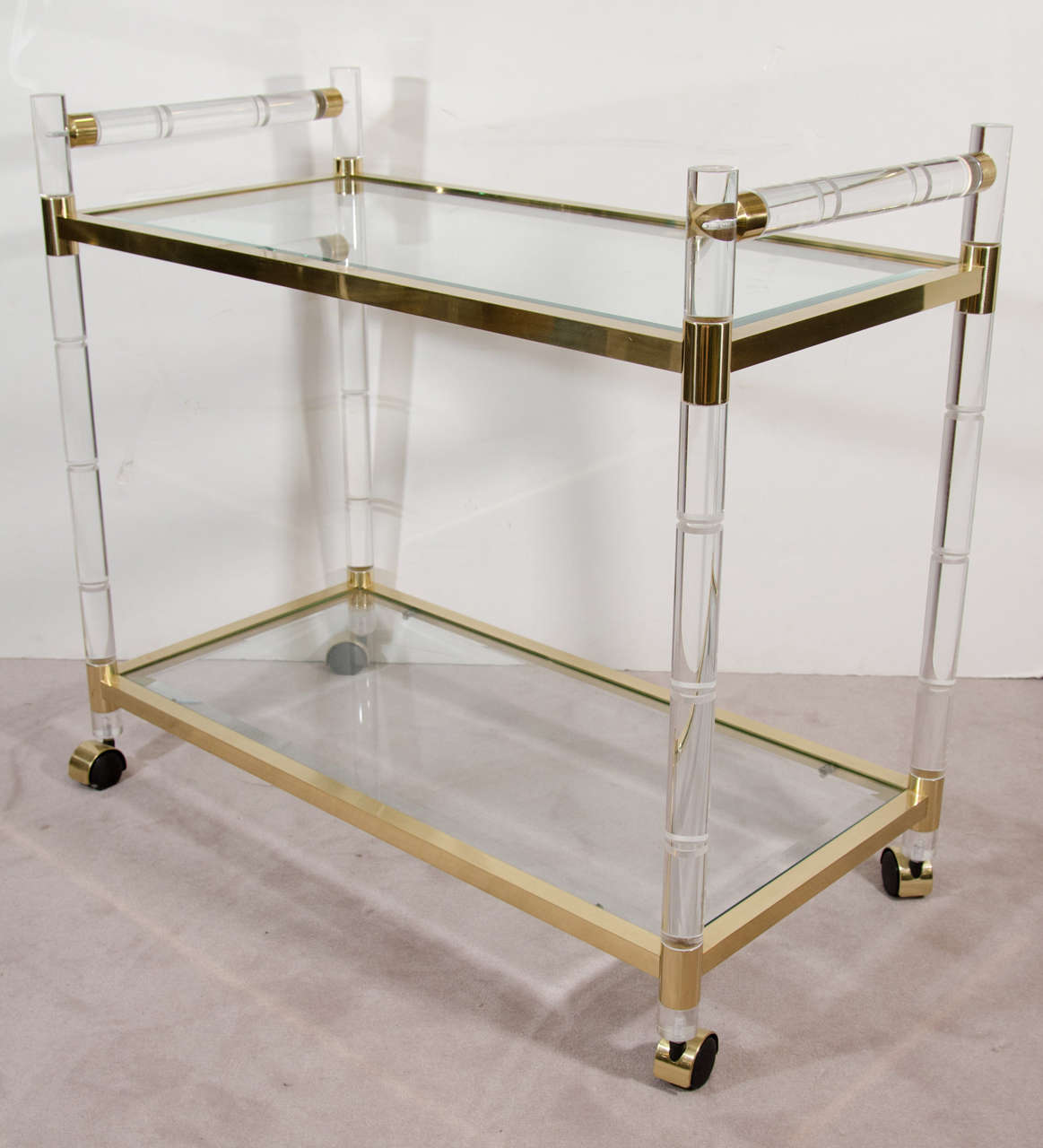 A mid century 1970s two-tier bar cart on casters designed by Charles Hollis Jones with a brass and stylized bamboo motif Lucite frame.

Good vintage condition with some minor scratches on Lucite consistent with age and use.