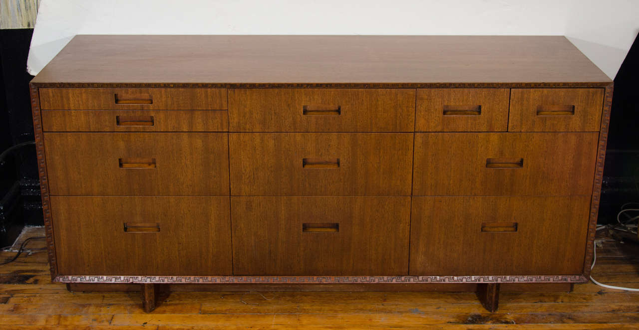 A vintage walnut Frank Lloyd Wright nine-drawer dresser or side board by Heritage-Henredon. The piece has carved geometric banding, and is marked on the inside of one drawer.

Good vintage condition with age appropriate wear.