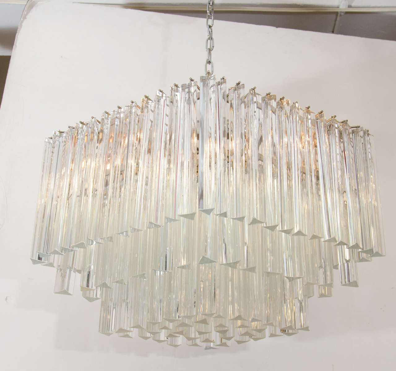 A mid century 1950s three-tiered Italian chandelier by Venini with crystal prisms suspended from a chrome frame. The chandelier drops 24