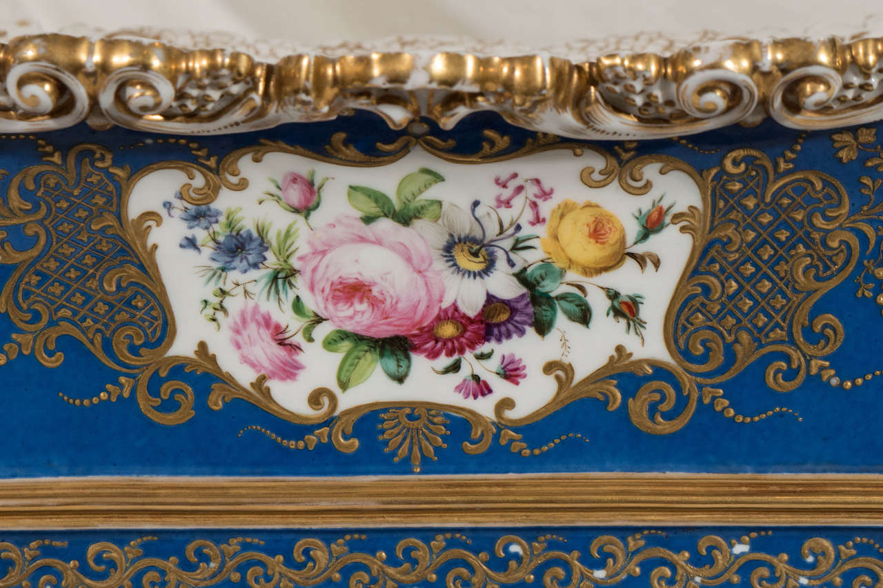 An exceptional French jardiniere and stand painted in rich blue with lavish gilt. It is finely painted front and back with bouquets of garden flowers.
 The rim is molded and enriched with berried foliage and shells. The bottom of the jardiniere is