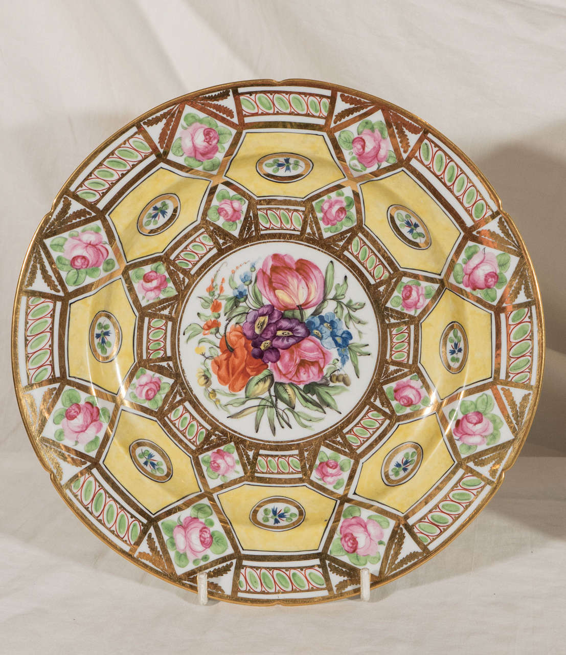 A pair of Regency Period Coalport dishes in the remarkable Church Gresley pattern decorated with yellow ground hexagons, pink roses, green leaves, and exceptional gilding, all surrounding a central roundel painted with beautiful bouquets of flowers.