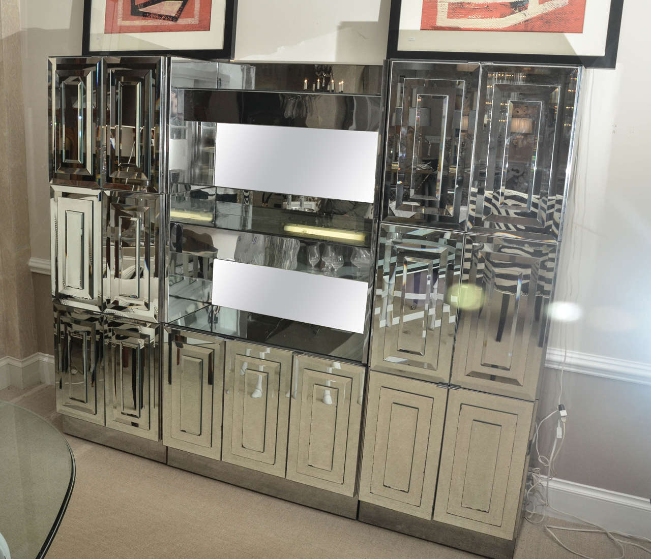 Spectacular Mid-Century mirrored dry bar Ello Furniture. It is made up of seven cabinet sections with beveled mirrored doors. It has under shelf lighting and one cabinet is lit.