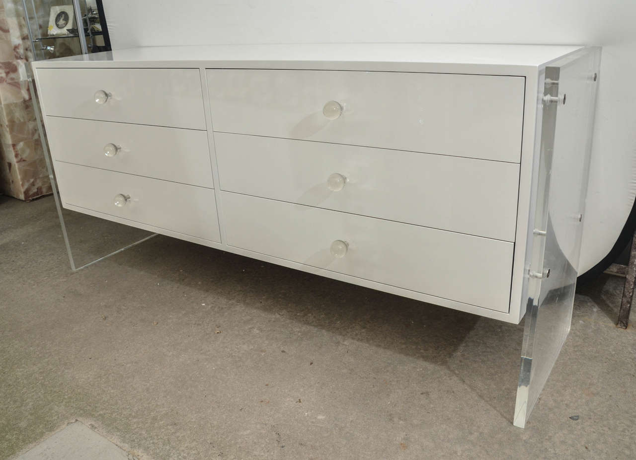 Attractive and stylish Mid-Century white lacquer six-drawer commode with Lucite sides. The Lucite sides are 1 inch thick. The commodes has glass knobs as drawer pulls.