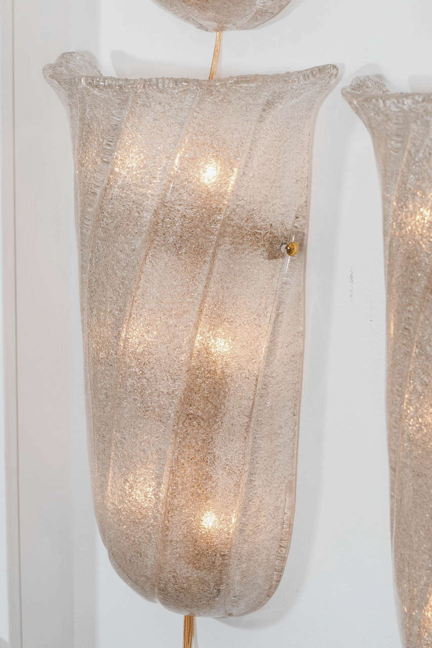 Pair of frosted Murano glass sconces with twisted fluting and brass finial detail.