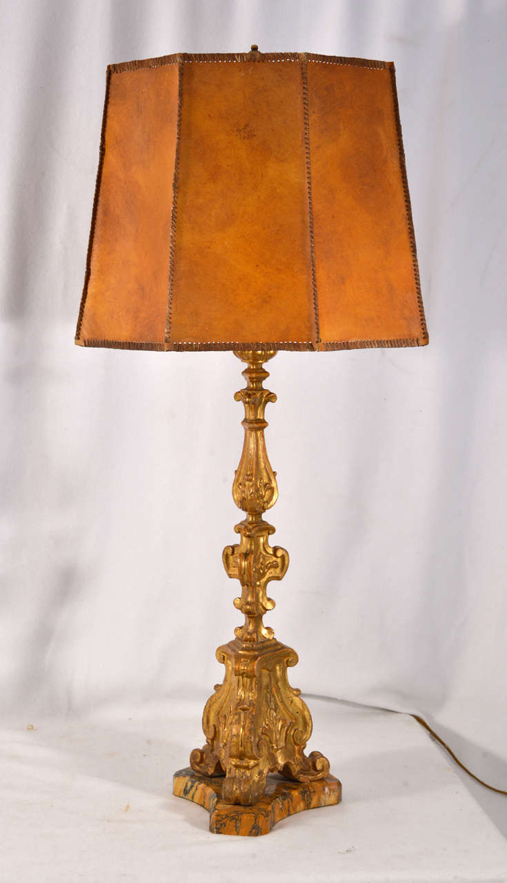 Beautiful, Hand carved Wooden Italian  Gilt Alter Candles mounted on custom crafted marble bases converted to table lamps with original, hand made leather lamp shades.  Candlesticks and lampshades have minor wear consisstant with age and use. 