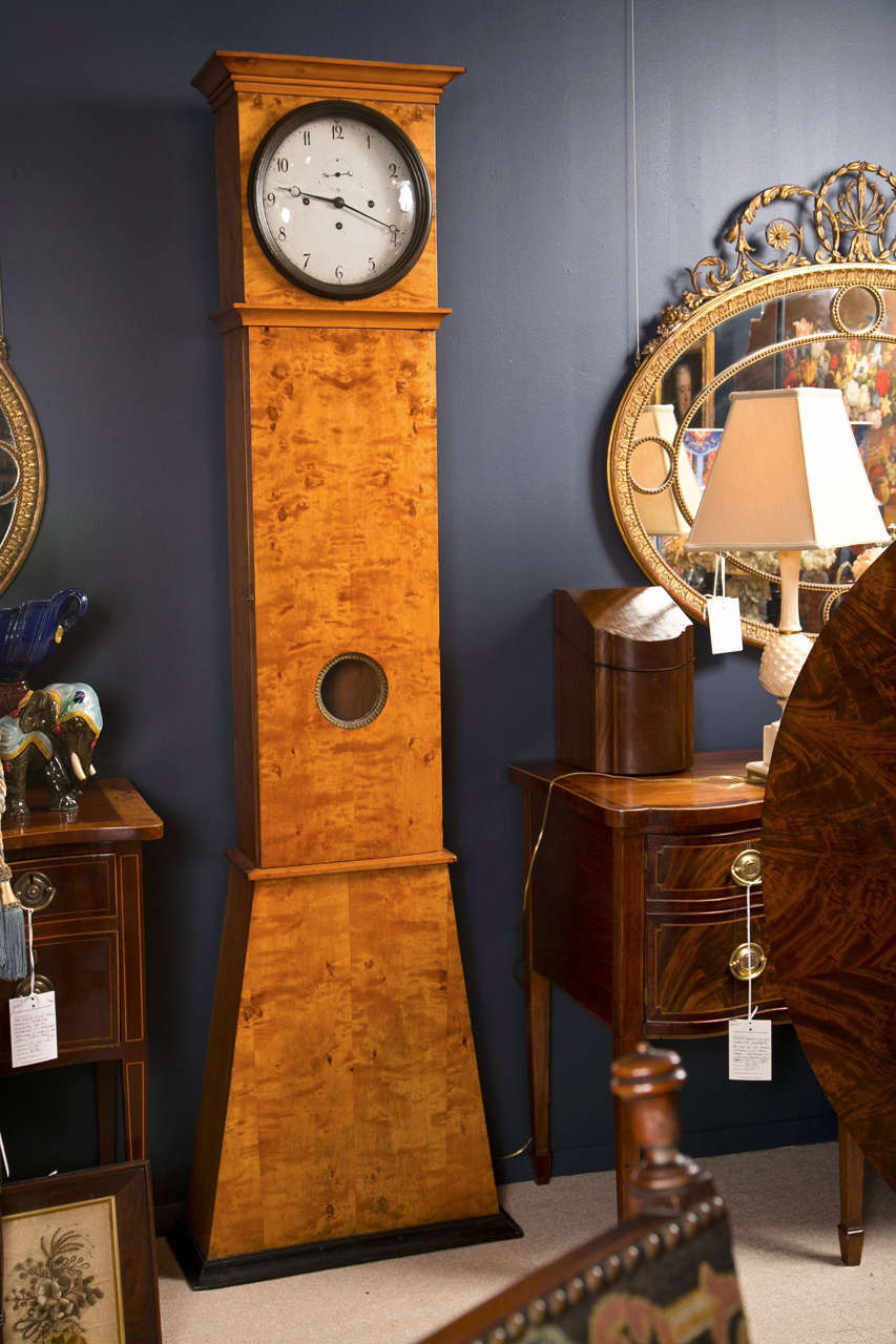 A Swedish birchwood tall case clock of traditional tapered form with an ebonized plinth and clock face molding.