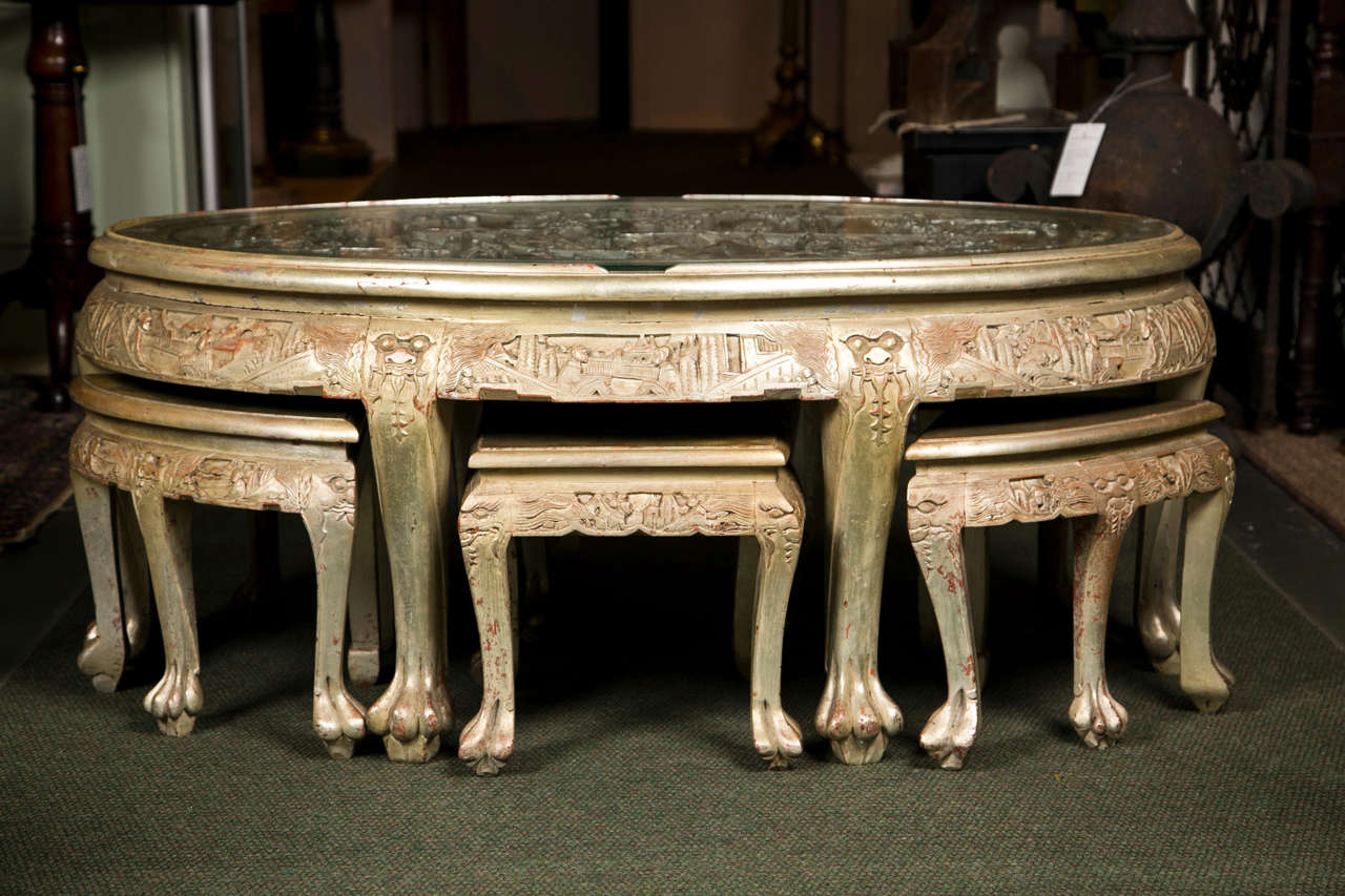 A magnificently carved, silver leaf cocktail table with six inserts and decorated with Asian motif. Attributed to James Mont.