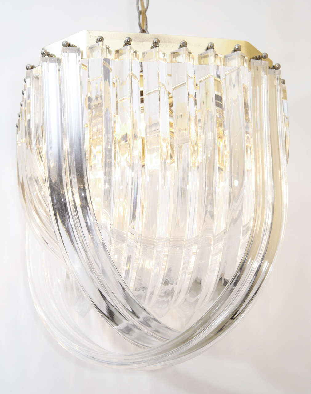 Sparkly and pretty lucite chandelier. The chandelier has lucite loops or ribbons hanging from a gold tone brass armature. Located at ABC Home, 646-602-3519
