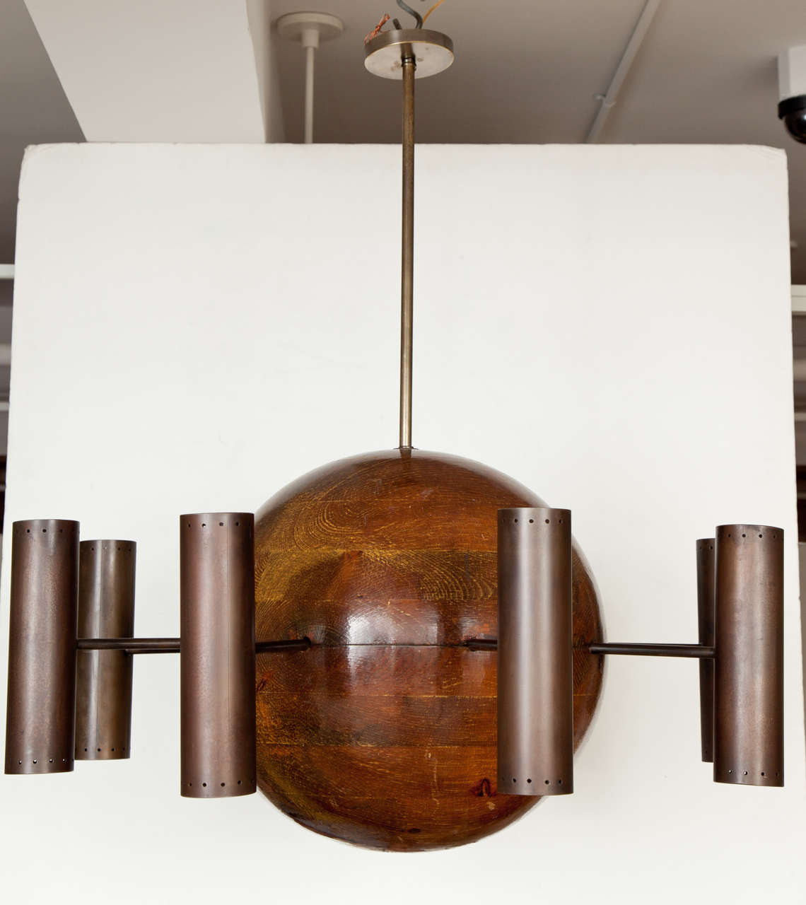 A massive oak sphere centers eight arms with pierced cylindrical patinated steel shades. Each shade contains two lights, one facing up, one down. Hand-made craftsman piece, Northern California, early 1960s. Newly rewired. Chandelier body is 22