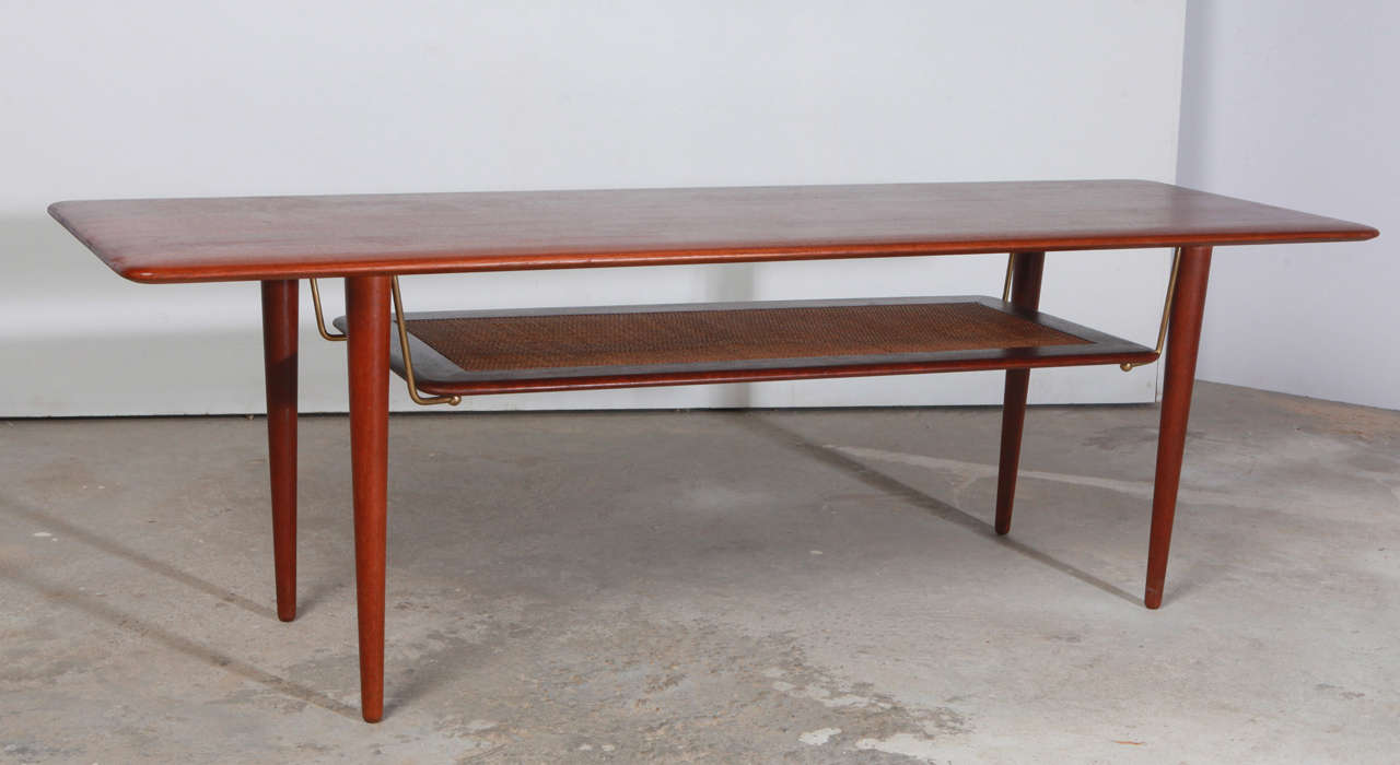 Solid teak danish modern coffee table with caned lower shelf designed by Peter Hvidt.