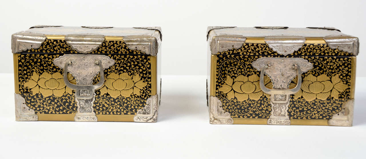 Pair of beautiful black lacquered small boxes with a gold foliage decor. On the back, on the front and on the top (probable) Date family Mon. Corners, hinges and handles in carved silvered metal with vegetal scrolls reminding the boxes