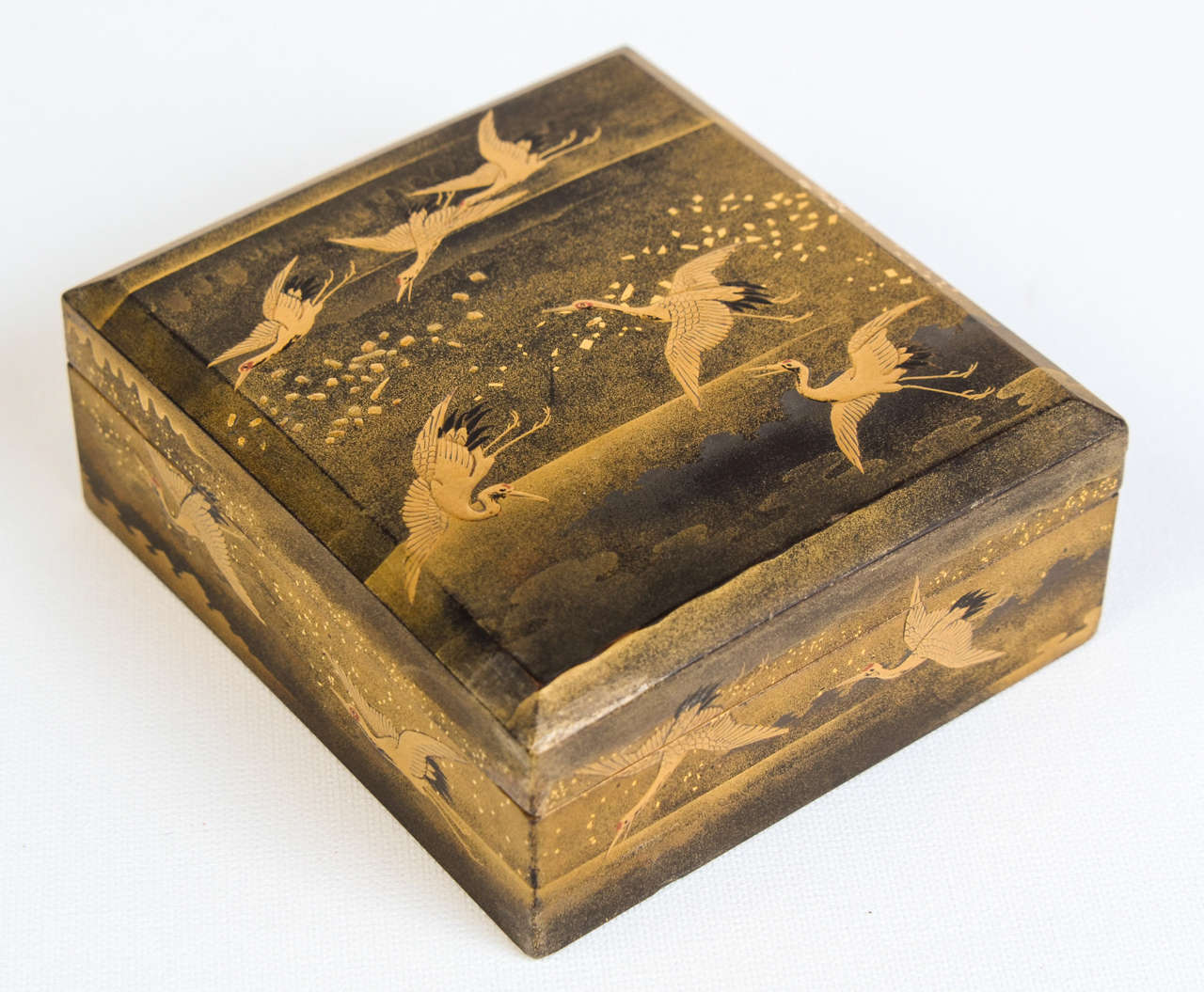 Beautiful small gilded lacquered box with a decor of cranes flying in a cloudy landscape. Nashi-ji lacquer inside.