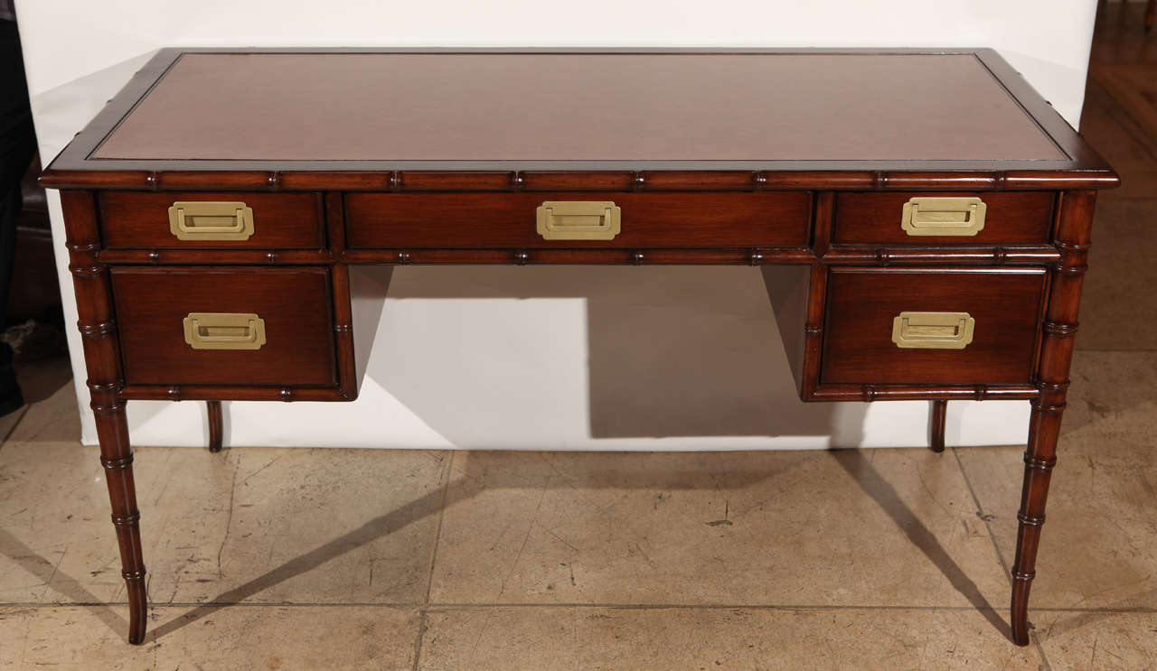 A mid century faux bamboo desk by Drexel. It is newly refinished in a dark walnut finish. Gold painted metal hardware. Stamped Drexel inside one of the drawers. Desk top is wood but made to look like leather.

Leg clearance is 24 inches.