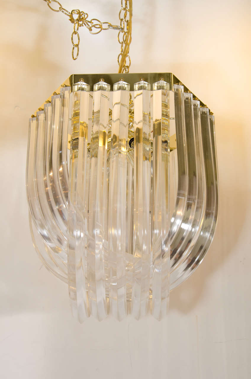 A set of three vintage Lucite chandeliers with Lucite prisms bent into loops, and suspended from brass frames. The small and large chandeliers have six sided frames, and the medium size chandelier has a circular frame.

Dimensions:
Small: 20