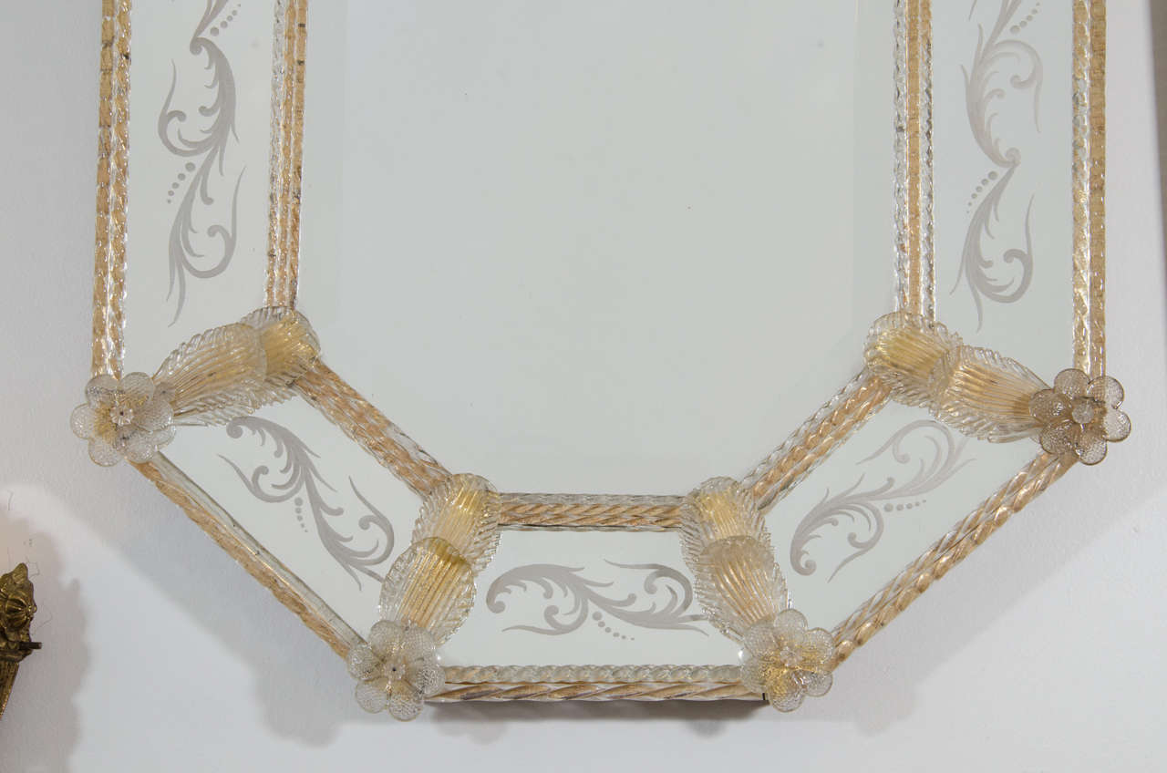 A mid century 1960s Italian octagonal wall mirror with gold flecked Murano glass, floral accents, and etching.

Good vintage condition with age appropriate wear.