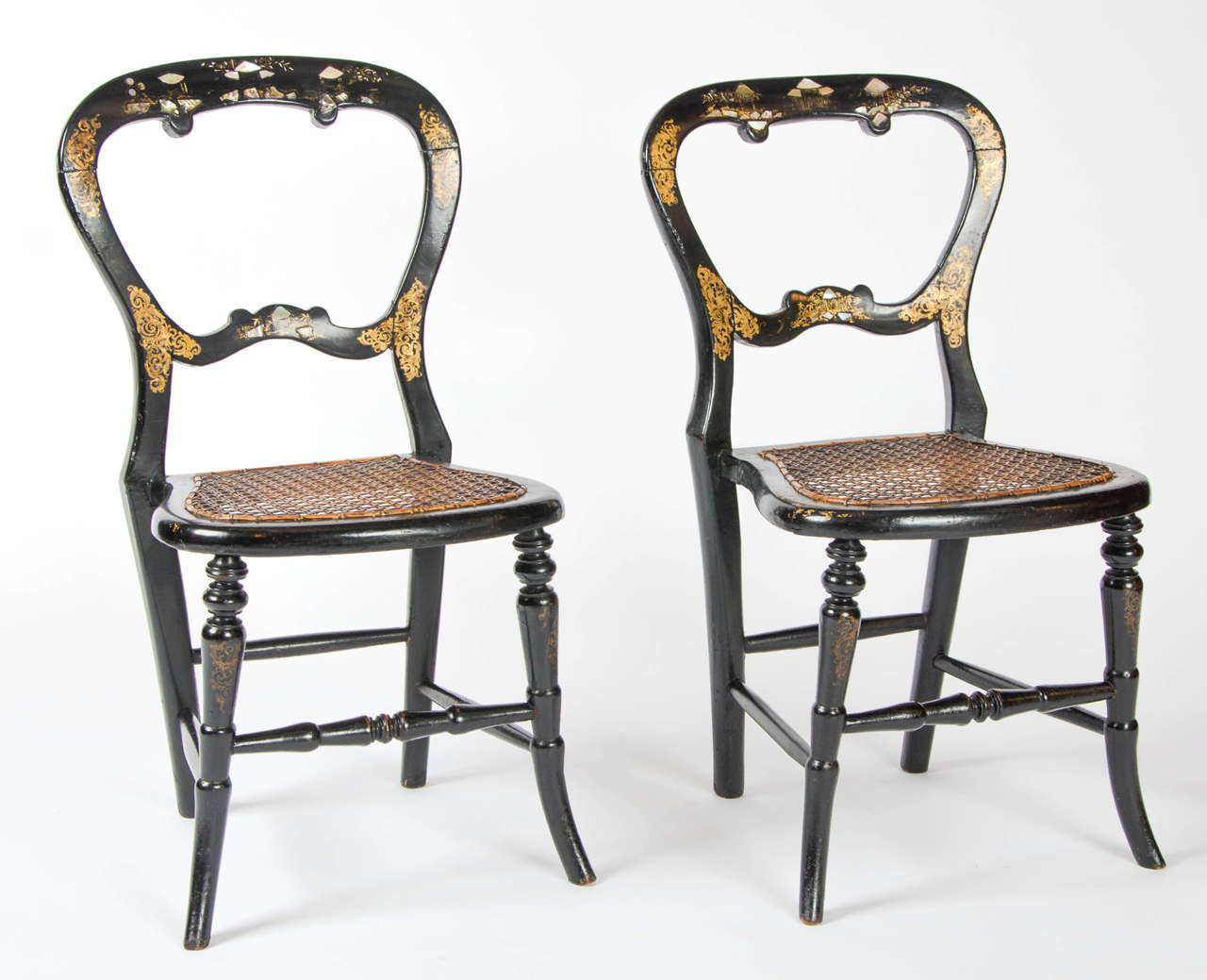 A pair of mid Victorian period children's chairs in papier-ma^che´ with cane seats and balloon backs inlaid with mother-of-pearl and gilt decoration throughout.