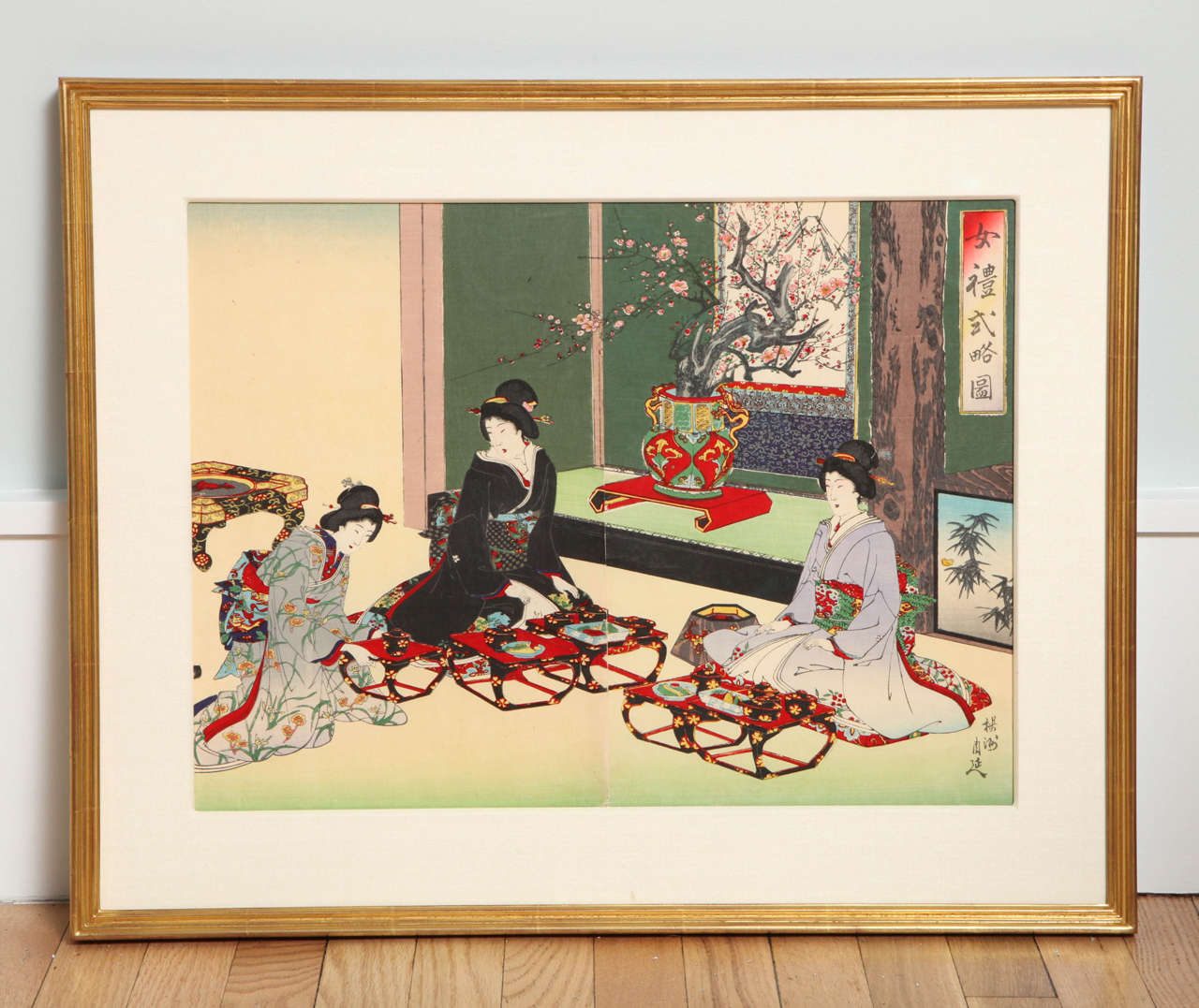 This Meiji-period color woodblock by Toyohara Chikanobu (1838-1912) depicts three elegant female courtiers in traditional dress taking refreshments. This diptych, from the issued triptych, has been mounted in a silk-wrapped mat fitted in a giltwood