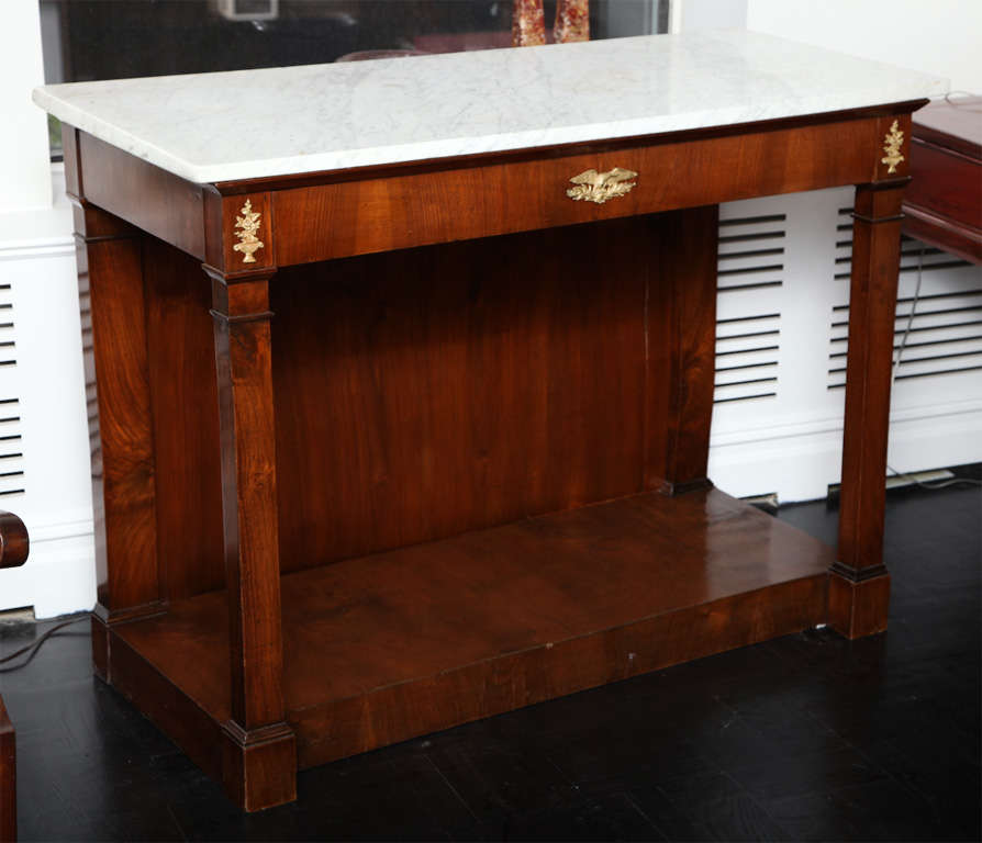 Late 18th Century walnut console, white marble top, drawer in apron with applied mounts, supported on columns with plinth base.