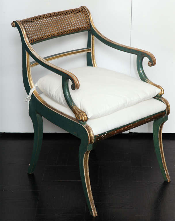 19th Century green painted  & giltwood open arm chair, cantered cane back railing, downswept arms on scrolled supports, saber legs