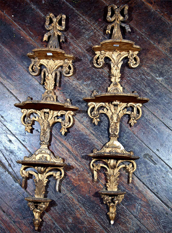 Carved and gilt French style three shelf wall bracket pair. Well carved with acanthus leaves and French bows.