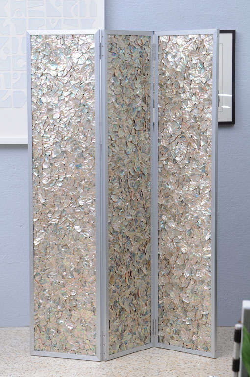 We love the juxtaposition of the precision, machine-tooled aluminium frame with the crazy-quilt, rainbow patchwork of natural abalone shell panels. The reverse is a subtly stunning series of shimmery mica-flecked, sand-textured strie beige on silver