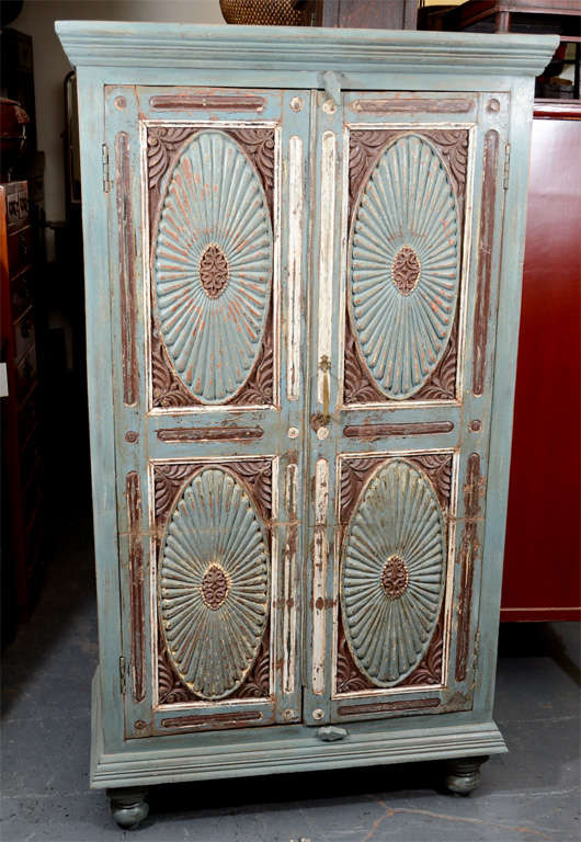 Teak armoire with teal and mahogany hues and floral imprint doors. With swivel latches for door locks