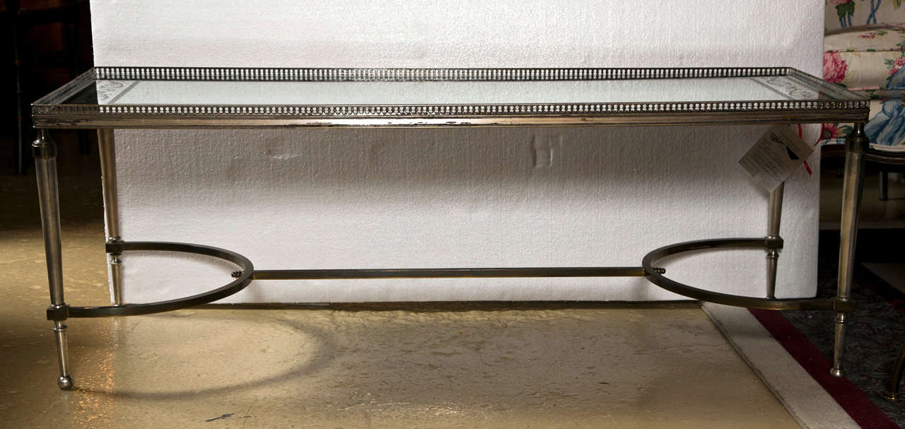 Vintage French coffee table in the Hollywood Regency taste, circa 1960s, Chrome and brass with a silver leaf and ebony vine design mirror glass top. 