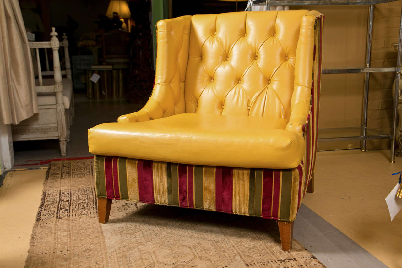 Pair of mid-century modern wing chairs, circa 1970s, upholstered in yellow leather with tufted back and cushioned seat, back, sides, and front bottom are upholstered in striped fabric, raised on squared tapering legs.