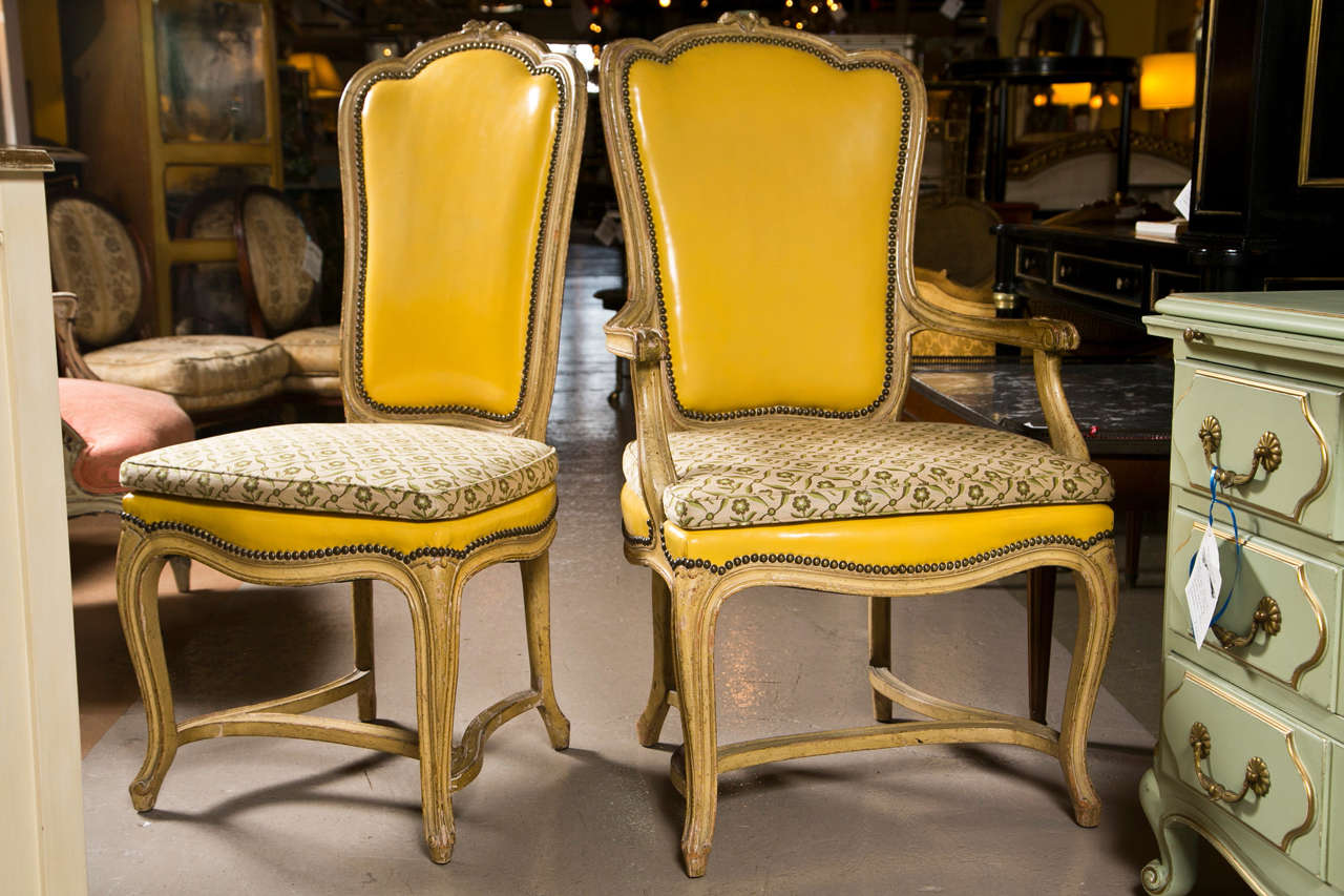 Beautiful set of 10 French Provincial style dining chairs by Jansen, consists of 2 armchairs and 8 side chairs, distress-painted wood frame, upholstered in yellow leather decorated with nail studs, padded seat, raised on cabriole legs with H