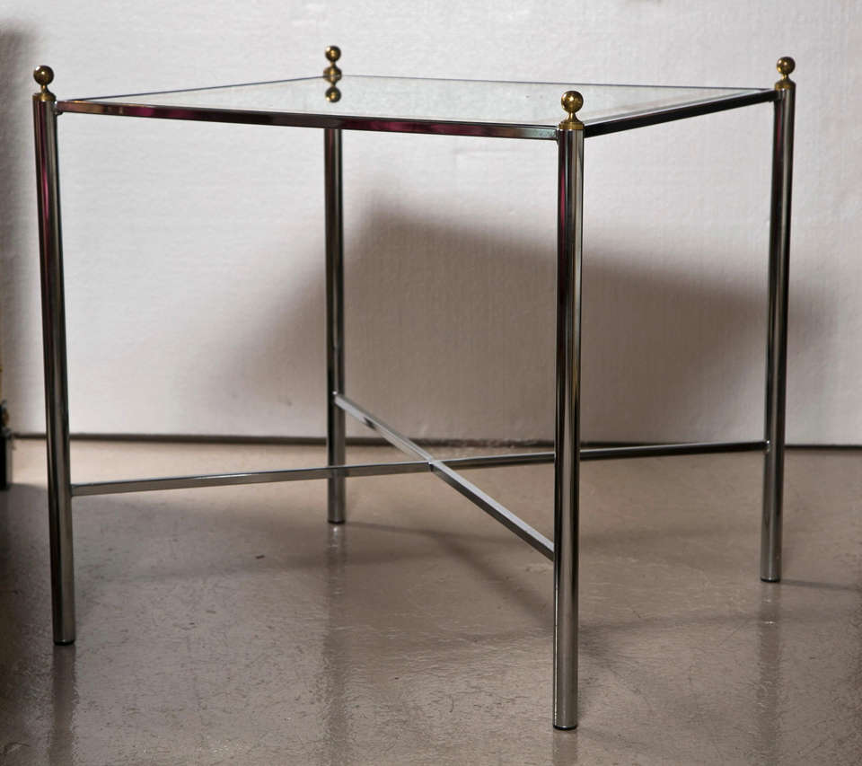 Pair of Mid-Century Modern style side tables by Jansen, each has square silver-leaf glass tops inserts on a chrome base with X-stretcher. By Jansen.