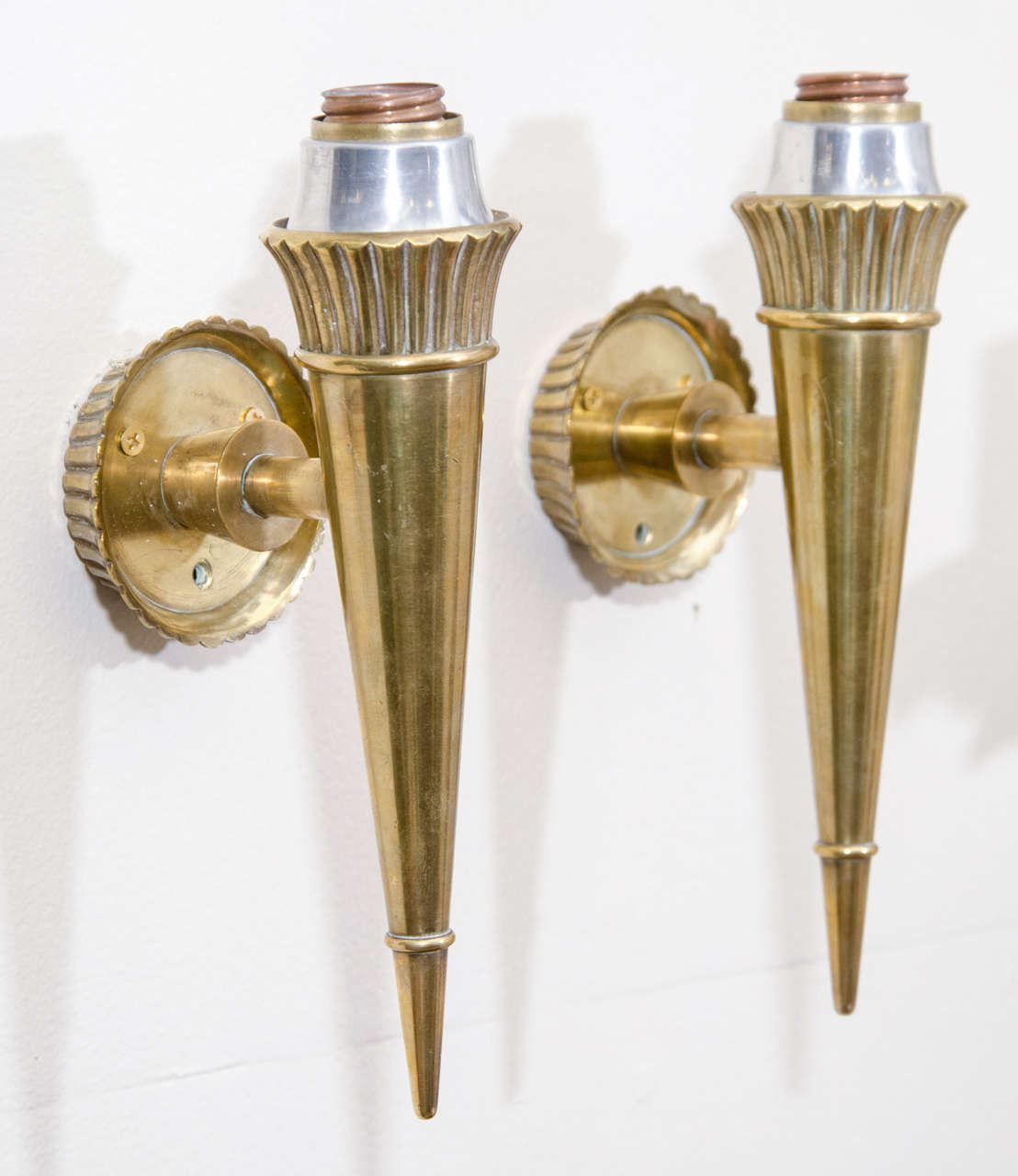 A pair of wall mounted fixtures in bronze with a conical shape. They are attributed to Genet and Michon. Euro. wiring and sockets.
