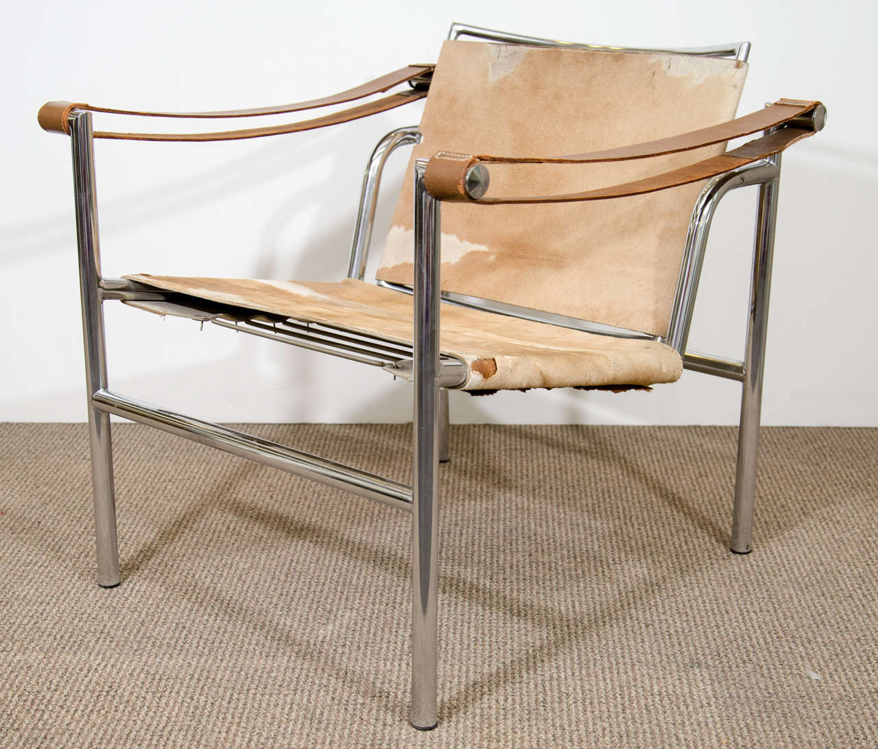 A vintage LC1 sling chair in cowhide with adjustable back, leather armrests and a tubular chrome frame. The piece was designed by Le Corbusier and manufactured by Stendig.