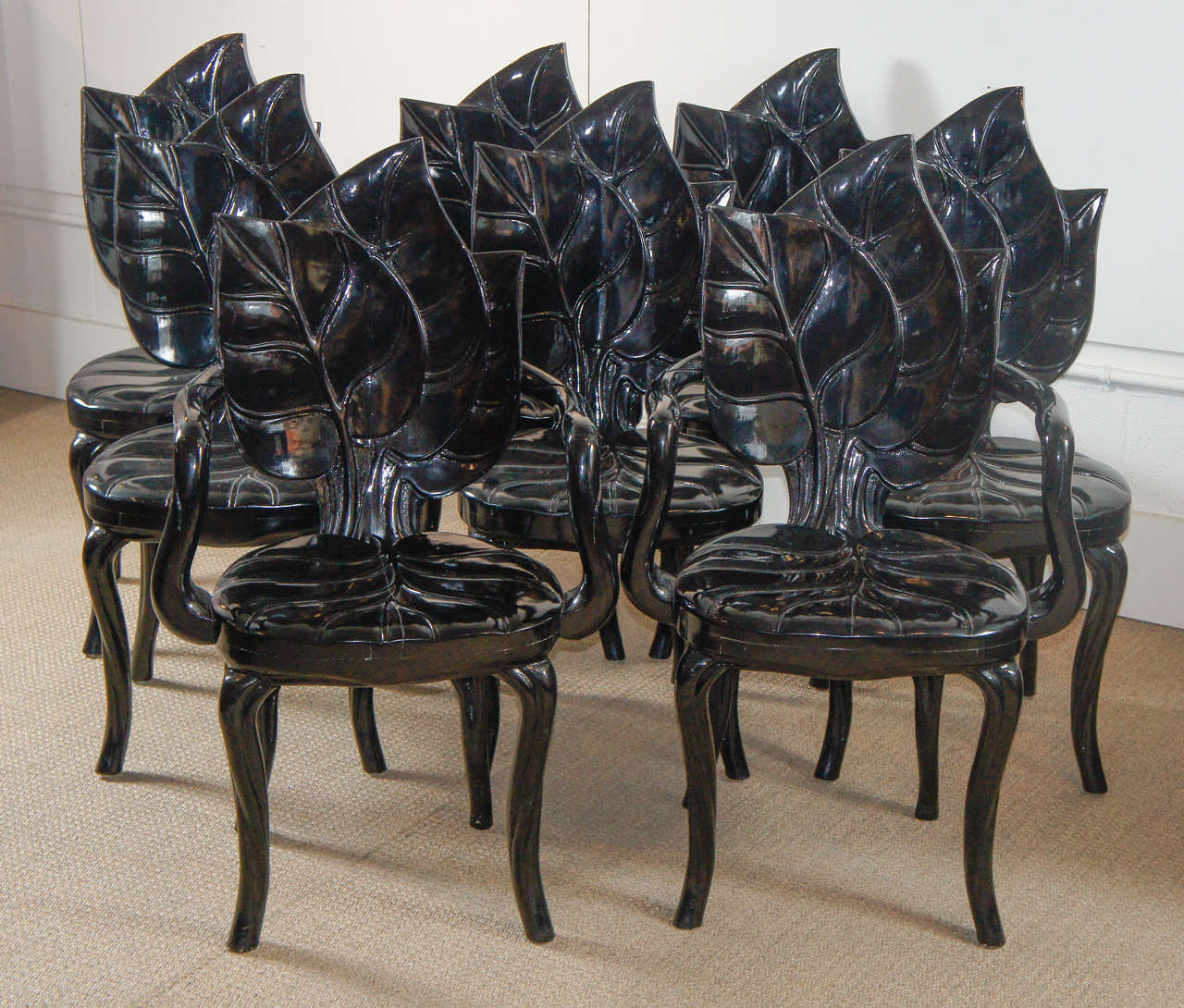 Here  is a beautiful group of eight black lacquered palm leaf chairs including two arms. The chairs are carved out of solid wood and has matching back detail. The chairs have a high gloss black lacquered finish.