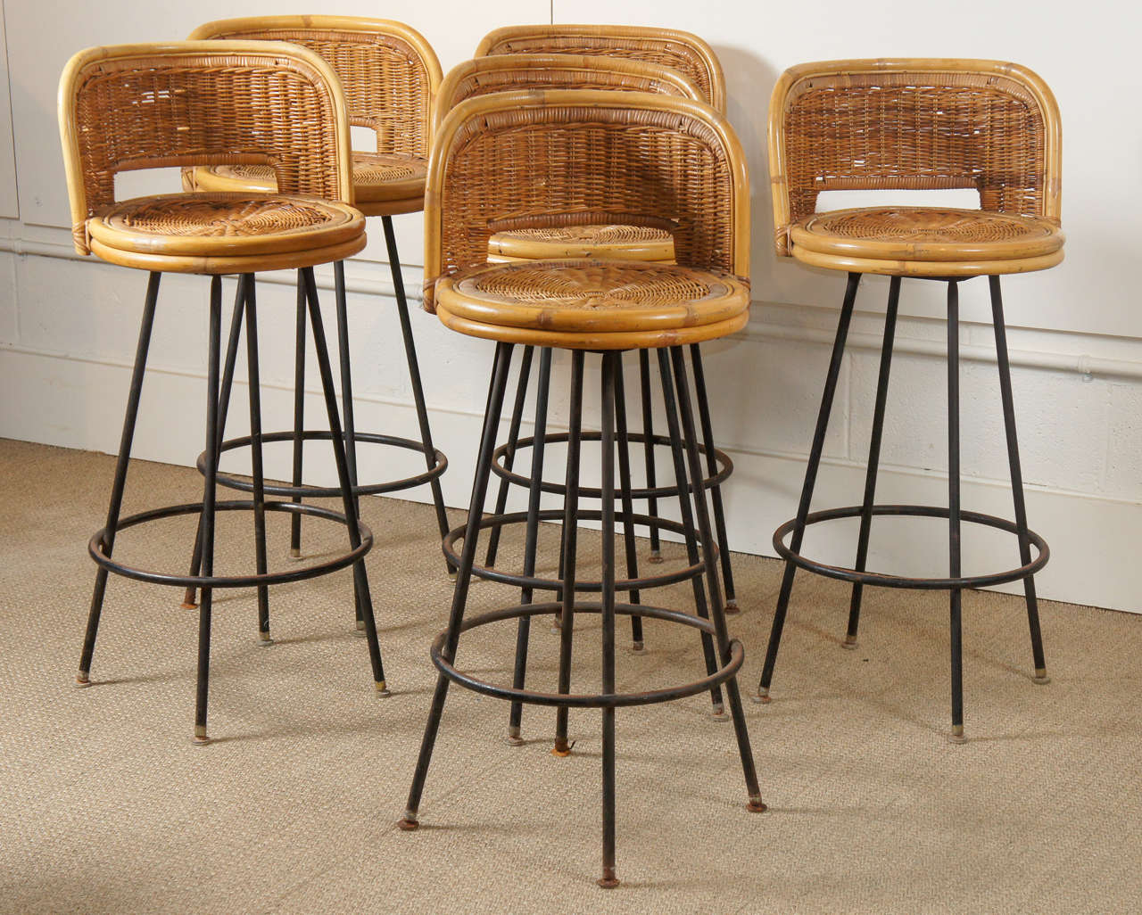 Here is a group of vintage rattan barstools with black iron bases and a swivel mechanism. The stools are available as singles.