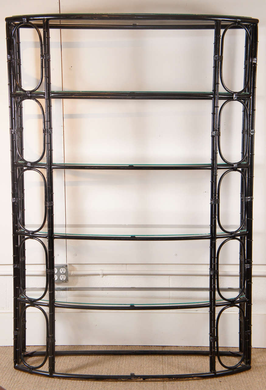 Here is a beautiful bamboo motif etagere made of steel in a black lacquered finish. The glass shelves sit on top of brackets and are fixed.