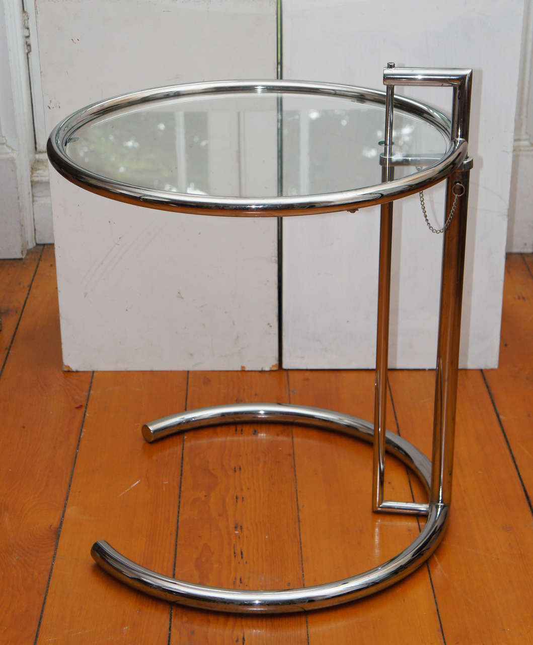 Eileen grey iconic style E1027 adjustable chrome and glass table. The
circular top on a ratchet mechanism, above a circular base.