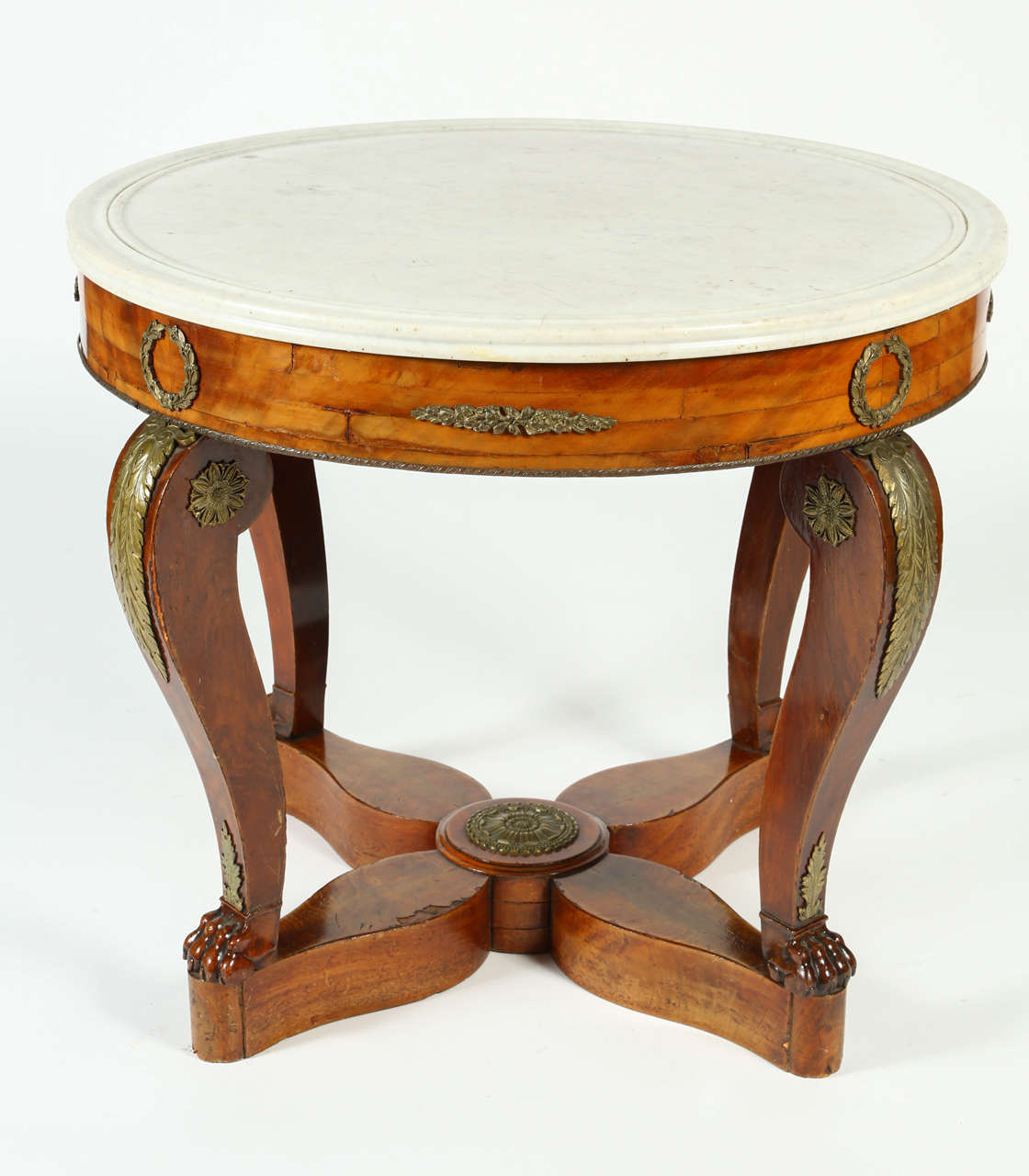 This Gueridon table from the French Restoration Era has a beautiful flame mahogany veneer and a white marble top. Delicate gilt-bronze garniture depicting laurel wreaths, palmettes, and roses decorate the apron, legs, and the star-shaped base. The