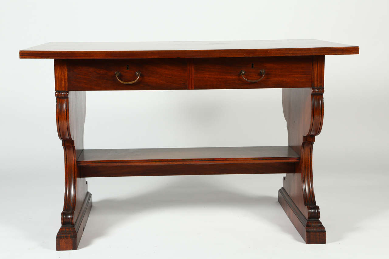 This wonderful mahogany center table is from the estate of Doris Duke. 
A rectangular top sits above a frieze which houses a pair of drawers. Trestle supports are carved with acanthus scrolls. This would make a wonderful desk in a library or as a