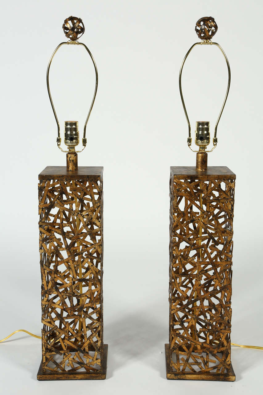 Unique transitional lamp in an antique gold leaf finished hand forged iron. The hand finishing process used on this lamp lends an air of depth and richness not achievable by less time-consuming methods. The unique design of these lamps allows them