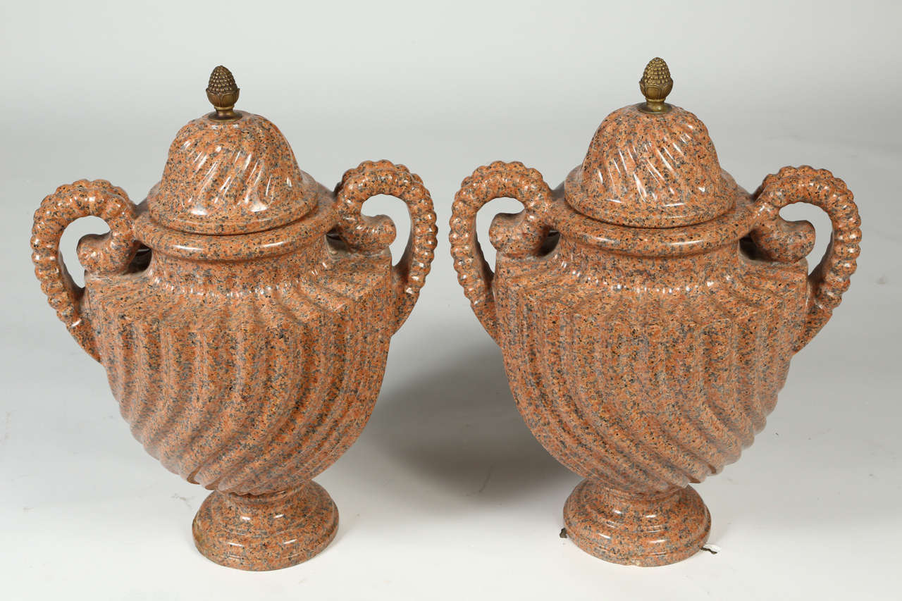 This large pair of highly carved urns with spiraled fluted urns are flanked by pierced scroll handles and topped by removable lids with circular bases.
