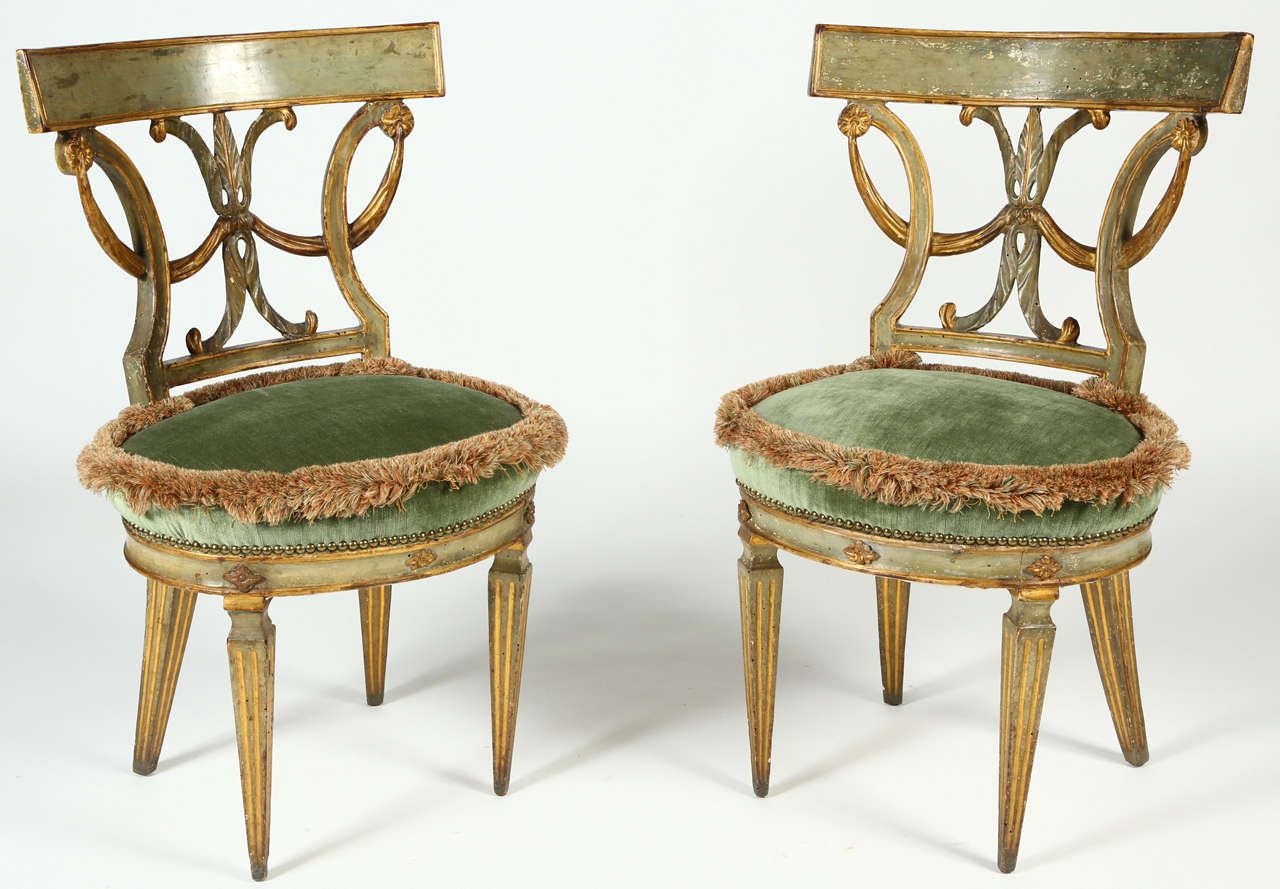 This pair of 18th Century, Italian side chairs embody the graceful lines of the Neoclassical style.  The Etruscan curve of the back rests surmount a carved back splat depicting a ribbon and rosette motif. The rear out-curved tapering 