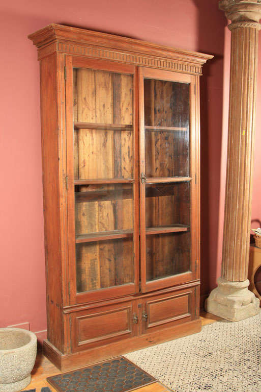 19TH CENTURY BOOKCASE..SOLID TEAK WOOD INCLUDING SHELVES. SIMPLE DESIGN AND PROPOSTIONS.FOUR GLASS INSERTS IN DOORS. MADE IN SRI LANKA.  ORIGINAL BRASS HARDWARE