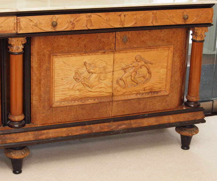 Large and impressive Italian three-cupboard credenza in burl veneer and ebonized wood; the body with highly detailed classical carvings in beech at the friezes and doors; corinthian columms separating the cupboard doors; bell feet; cream colored