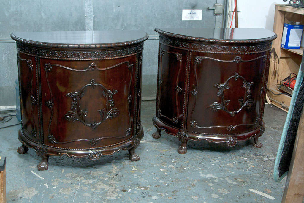 A Georgian Style Demilune Commode circa 1940s, dark mahogany, beautiful carvings, single door opens to a cabinet with one shelf, raised on claw and ball feet.