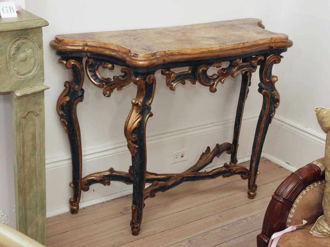 Pair of I8thc. Painted Italian Consoles.  Painted wooden consoles in black with elegant gold carvings on trestle, legs and apron. The top is also wood with gold faux marbre finish and complemented by gold base with rounded edge..