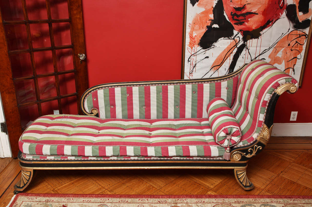 This daybed stands out for its large-scale. With outward scrolling upholstered side and downswept back within an ebonized surround with gilt acanthus and lotus leaf decoration; the tufted seat over a gilt-banded rail supported on outswept feet with