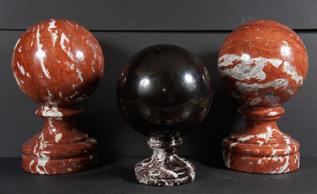 This three-piece grouping of specimen marble spheres can be sold as the group or as a pair  ( the left and right are a pair or as a single in the middle) and a single. The marble is dramatically veined in the case of the ocher-colored spheres or