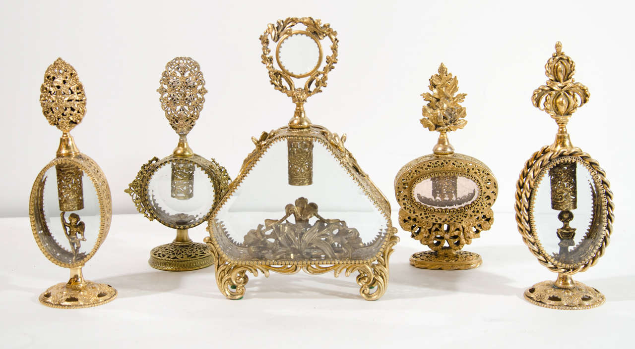 Exquisite collection of antique perfume bottles (Set/7 or Sold Individually). Perfume bottles comprised of hand made gilded brass with ornate and intricate filigree designs surrounding cut crystal glass.  All of the bottles have unique designs
