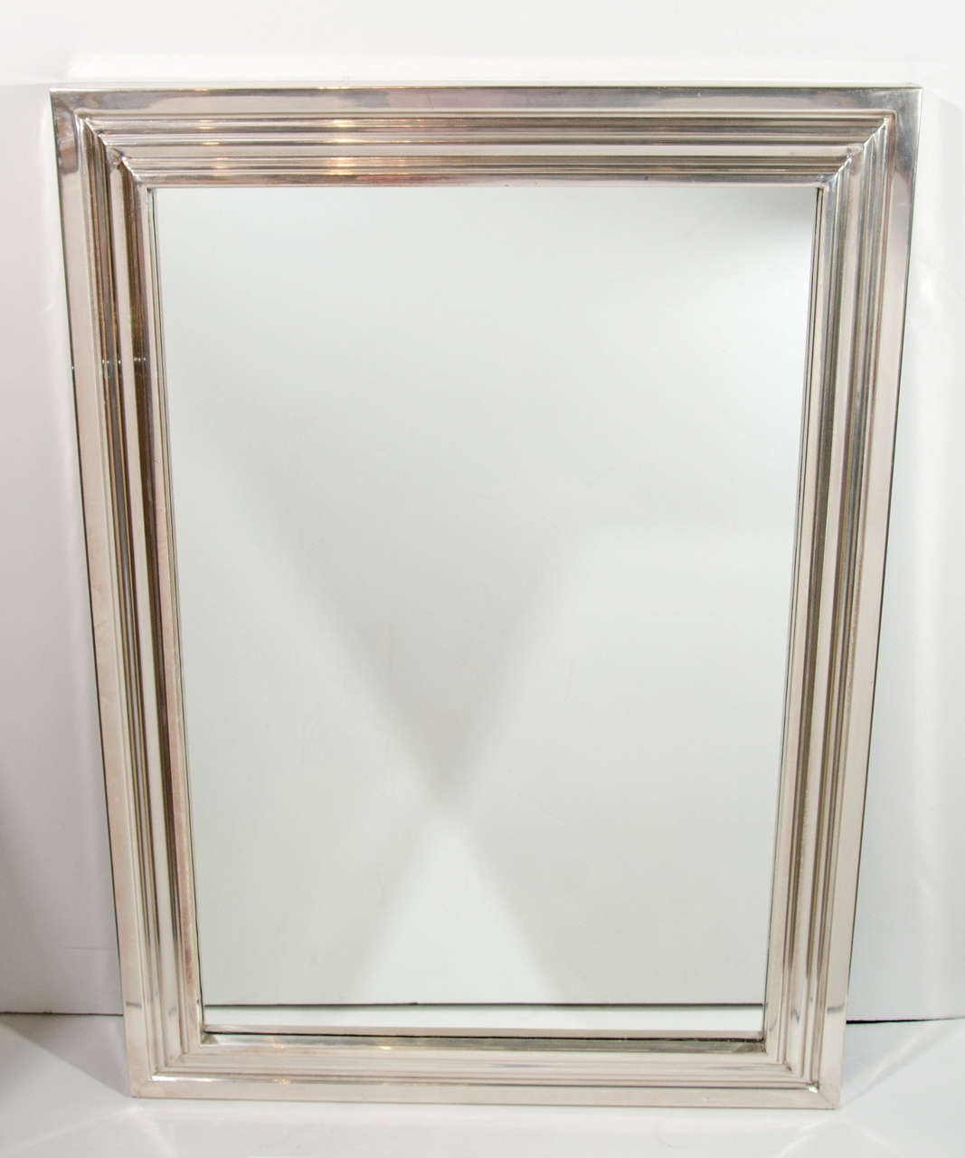Modernist mirror with inverted shadowbox form. The mirror is rectangular in shape and has hand-forged silvered metal (chromed) triple border frame design, with straight Classic lines.